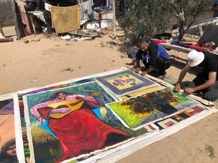 Artist Mohammed Al-Hawajri organizing paintings retrieved from his destroyed house and studio in Bureij Refugee Camp in Gaza, 2024. Courtesy of Dina Matter and the artist.jpeg